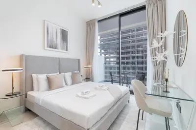 a white bedroom with a bed and a glass table at Stylish 1BHK by CzechIn Pool & Gym Prime JVC in Dubai