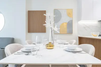 a white dining room table with a vase of flowers on it at Stylish 1BHK by CzechIn Pool & Gym Prime JVC in Dubai