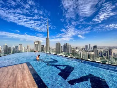 a man in a infinity pool on the top of a skyscraper at 5 Star Rooftop Infinity Pool with Burj Khalifa Views in Dubai