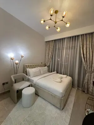 a bedroom with a bed and a chair and a chandelier at Studio Designer Azizi 41 in Dubai