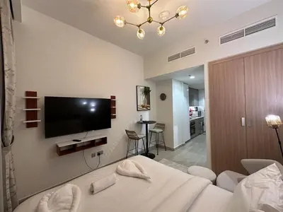a bedroom with a bed and a flat screen tv at Studio Designer Azizi 41 in Dubai