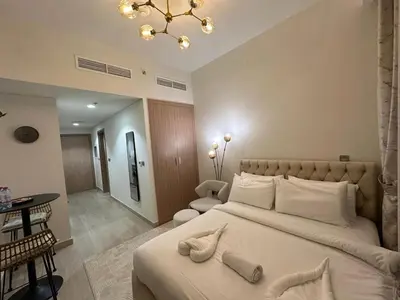 a bedroom with a large bed with a chandelier at Studio Designer Azizi 41 in Dubai