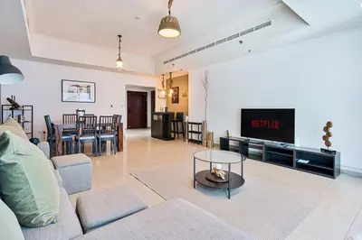 a living room with a couch and a tv at Spacious 2 BR With Pool, Gym and Kid's Playground in Dubai