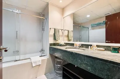 a bathroom with a large sink and a shower at Spacious 2 BR With Pool, Gym and Kid's Playground in Dubai