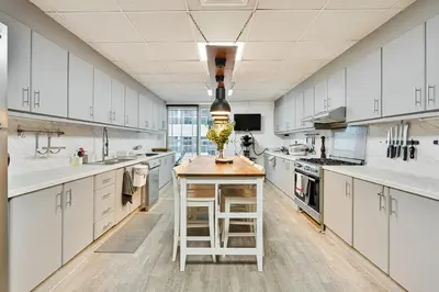 a large kitchen with white cabinets and a wooden island at Spacious 2 BR With Pool, Gym and Kid's Playground in Dubai