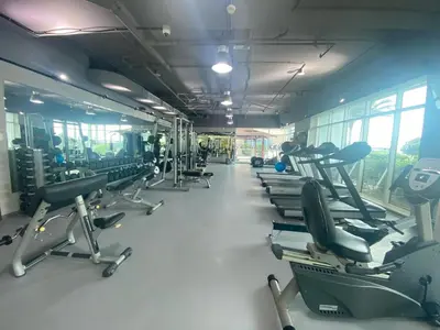 a gym with a row of treadmills and machines at Spacious 2 BR With Pool, Gym and Kid's Playground in Dubai