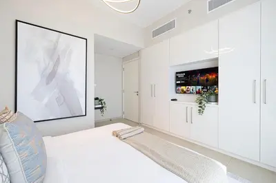 a white bedroom with a large painting on the wall at Elite 4 Bedroom Luxury Apartment, Burj Khalifa View, Opposite Dubai Mall, Infinity Swimming Pool in Dubai