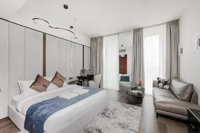 a bedroom with a large white bed and a couch at Modern Stylish Studio Apartment next to Burj Khalifa walk into Dubai mall in Dubai