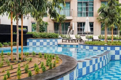 a hotel swimming pool with palm trees and chairs at Modern Stylish Studio Apartment next to Burj Khalifa walk into Dubai mall in Dubai