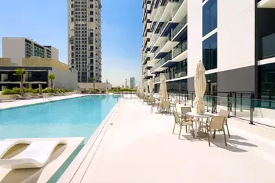 a swimming pool with tables and chairs next to a building at Close Proximity to Leisure Areas and City View 1BR, Binghatti Corner, Jumeirah Village Circle by Deluxe Holiday Homes in Dubai