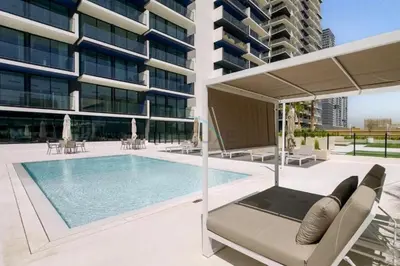 a swimming pool in front of a building at Close Proximity to Leisure Areas and City View 1BR, Binghatti Corner, Jumeirah Village Circle by Deluxe Holiday Homes in Dubai