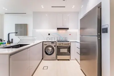a white kitchen with a washer and dryer in it at Close Proximity to Leisure Areas and City View 1BR, Binghatti Corner, Jumeirah Village Circle by Deluxe Holiday Homes in Dubai