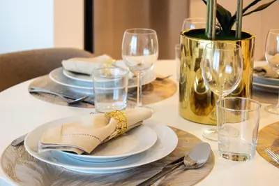 a table with plates and glasses and a vase at Gorgeous 1BD Apt with beach access in Grand Bleu in Dubai