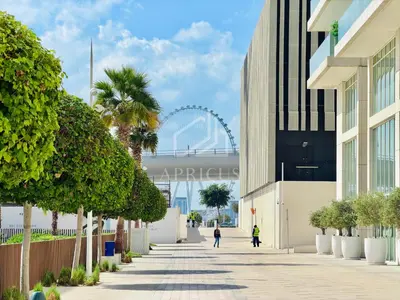 a walkway with a ferris wheel in the background at Gorgeous 1BD Apt with beach access in Grand Bleu in Dubai