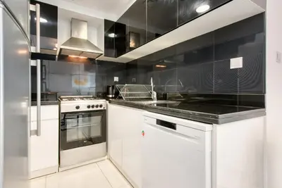 a kitchen with white cabinets and a black wall at HAVN - NEW 1 Bedroom Apartment in Business Bay in Dubai