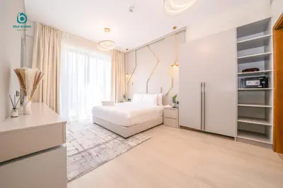 a bedroom with a white bed and a large window at Blue Breeze - Chic & Cozy 1 BR Getaway in Al Furjan in Dubai
