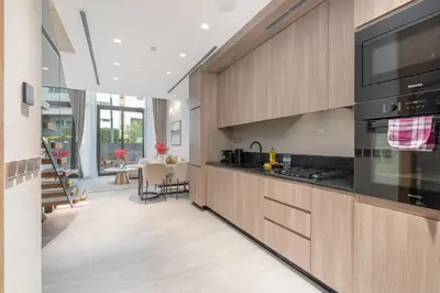 a kitchen with wooden cabinets and black appliances at Elegant 1BHK by CzechIn Luxe Stay with Pool and Gym in Dubai