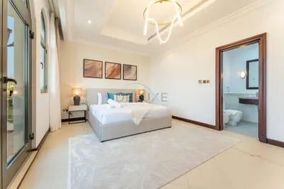 a white bedroom with a bed and a bathroom at Beachfront 6BR and Assistant's Room Villa with Private Pool, Palm Villa, Palm Jumeirah by Deluxe Holiday Homes in Dubai