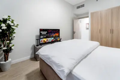 a white bedroom with a bed and a flat screen tv at Chic 1 BR with Port Views in Dubai