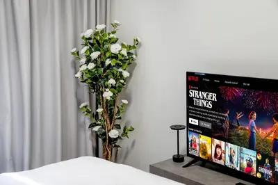 a vase of white flowers next to a tv at Chic 1 BR with Port Views in Dubai