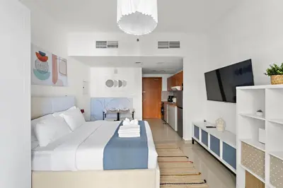a bedroom with a large bed and a tv at Modern Studio in Production City in Dubai