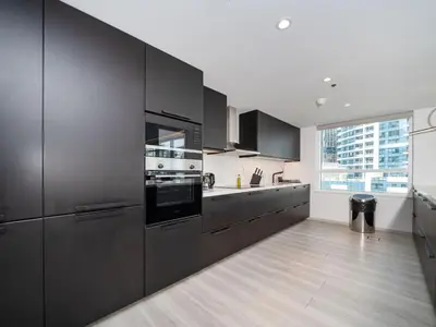 a kitchen with black cabinets and a large window at Waterfront Dubai Marina 3-Bedroom Sanctuary in Dubai