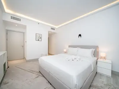 a white bedroom with a large white bed with two lamps at Waterfront Dubai Marina 3-Bedroom Sanctuary in Dubai