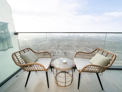 two wicker chairs and a table on top of a building at Elegant Studio in Bloom JVC with High-End Finishes in Dubai