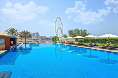 a large swimming pool with a ferris wheel in the background at Al Bateen - Two Bedroom in JBR with City Views in Dubai