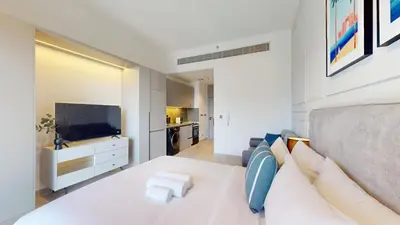 a bedroom with a large white bed and a kitchen at Mag 980 - Cosy Studio with City Views in Meydan in Dubai