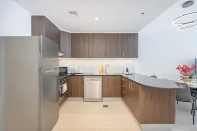 a kitchen with wooden cabinets and a stainless steel refrigerator at Stylish1BHK in Elite Residences, Marina with View in Dubai