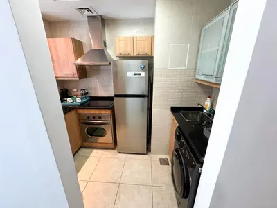 a small kitchen with a stainless steel refrigerator at Holiday Homes by DO- The Zumrud in Dubai