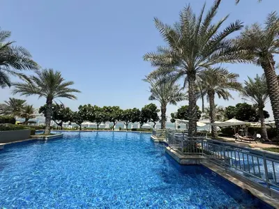 a swimming pool with palm trees in a resort at Bright 2 Bedroom Apartment, Beach & Pool Access in Dubai