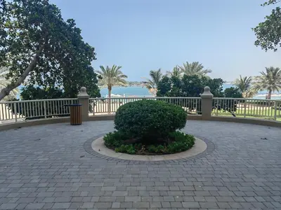 a brick walkway with a bush in front of a fence at Bright 2 Bedroom Apartment, Beach & Pool Access in Dubai