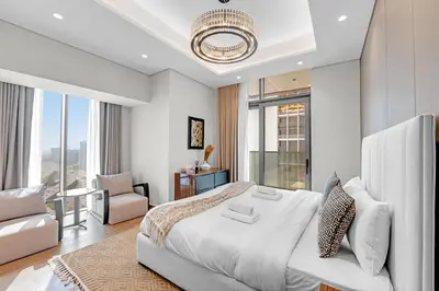 a white bedroom with a large bed and a chair at Breathtaking 2Bedroom in Nobles in Dubai
