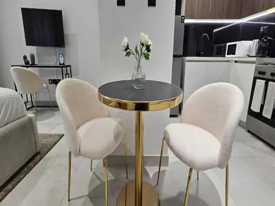 a table with white chairs and a vase of flowers on it at Luxury Studio in JVC in Dubai