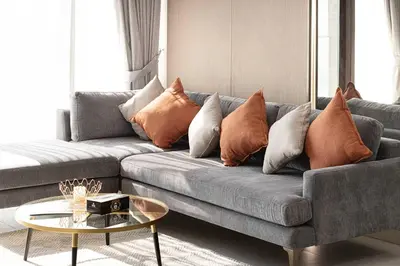 a living room with a gray couch with pillows at Spacious 1BR with Modern Amenities in Westwood Grande JVC in Dubai