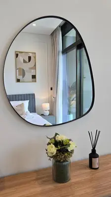 a mirror on a wall with a vase of flowers on a table at Relax in Style with Outdoor Pool and Burj Khalifa Views Nearby in Dubai