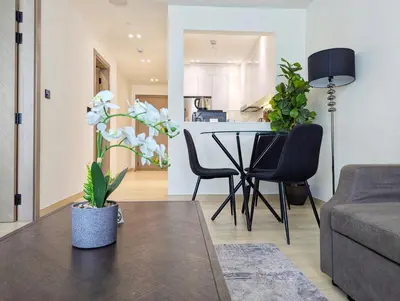 a living room with a table and chairs and a kitchen at Modern Luxury Fully Furnished 1BH Apartment in Binghatt Nova JVC - Easy Access to JBR, Circle Mall & Dubai Hills Mall in Dubai