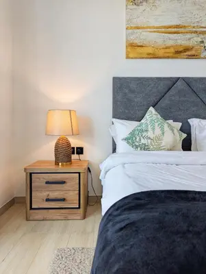 a bedroom with a bed and a nightstand with a lamp at Modern Luxury Fully Furnished 1BH Apartment in Binghatt Nova JVC - Easy Access to JBR, Circle Mall & Dubai Hills Mall in Dubai