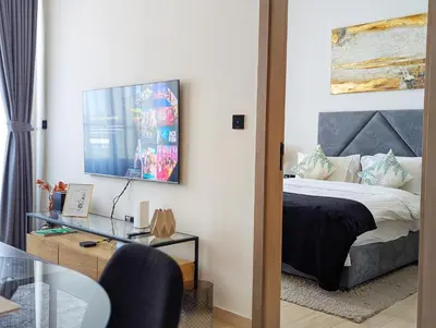 a bedroom with a bed and a desk with a glass table at Modern Luxury Fully Furnished 1BH Apartment in Binghatt Nova JVC - Easy Access to JBR, Circle Mall & Dubai Hills Mall in Dubai