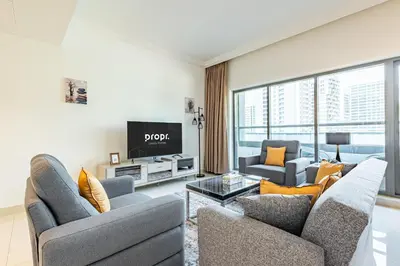 a living room with two couches and a tv at Spacious 1BR - Balcony & Pool View - Capital Bay in Dubai