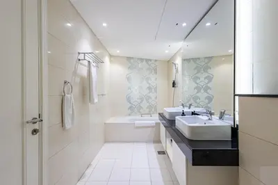 a white bathroom with a sink and a tub and a sink at Spacious 1BR - Balcony & Pool View - Capital Bay in Dubai