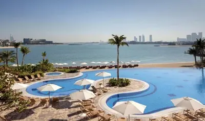a resort with a pool and a beach with umbrellas at TYS EXCELLENCE luxury apartment Palm Jumeirah DUBAI in Dubai