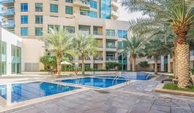 a swimming pool with palm trees in front of a building at HAVN - Studio in Downtown, 10mins to Dubai Mall in Dubai