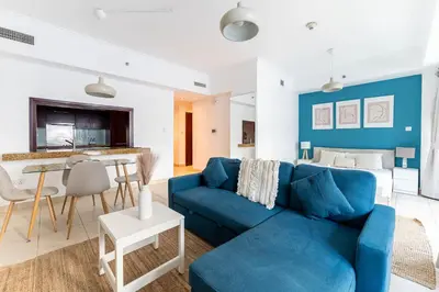 a living room with a blue couch and a table at HAVN - Studio in Downtown, 10mins to Dubai Mall in Dubai