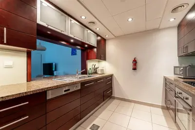 a large kitchen with wooden cabinets and a sink at HAVN - Studio in Downtown, 10mins to Dubai Mall in Dubai