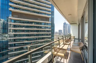 a balcony with chairs and a view of a tall building at Dubai Marina View - 2BR APT with Pool & Gym in Dubai
