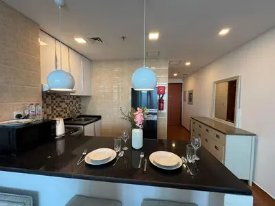 a kitchen with a table with plates and wine glasses at Cozy Studio Apartment Holiday Home l Perfect for Couples in Dubai
