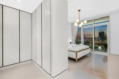 a white bedroom with a bed and a window at Sea View 2BR Near Beach Marina Walk & Dining Spots in Dubai